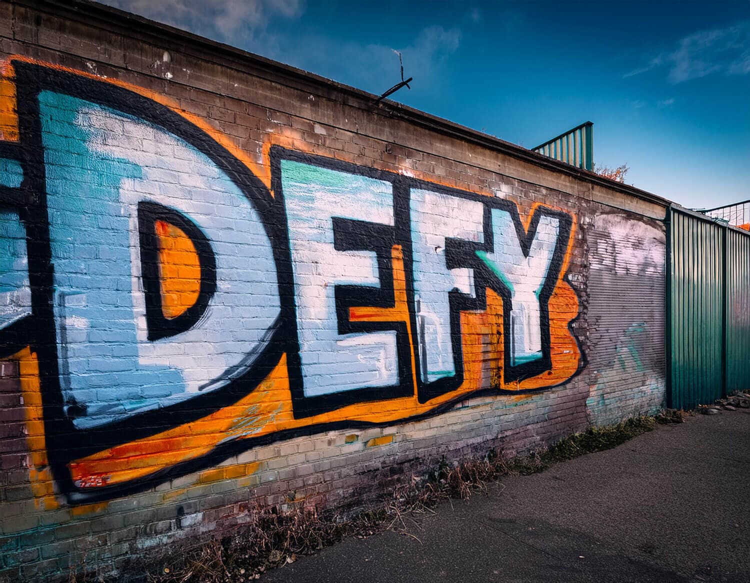 Defy words spray painted on a brick wall