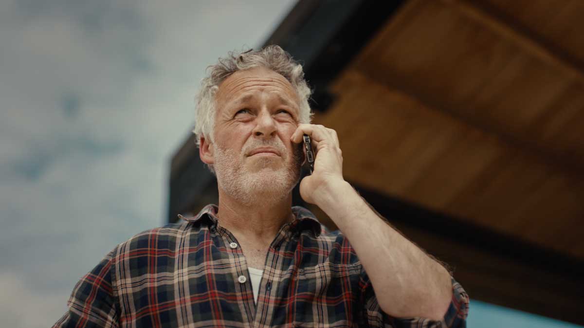 Man on the phone wearing a white and red checked shirt