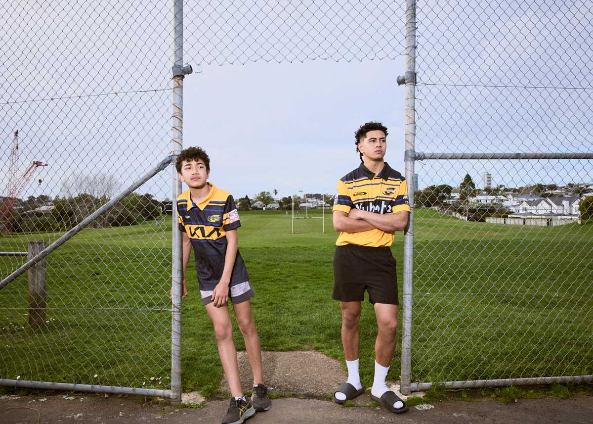 two boys in hurricanes jerseys standing in front of a rugby field